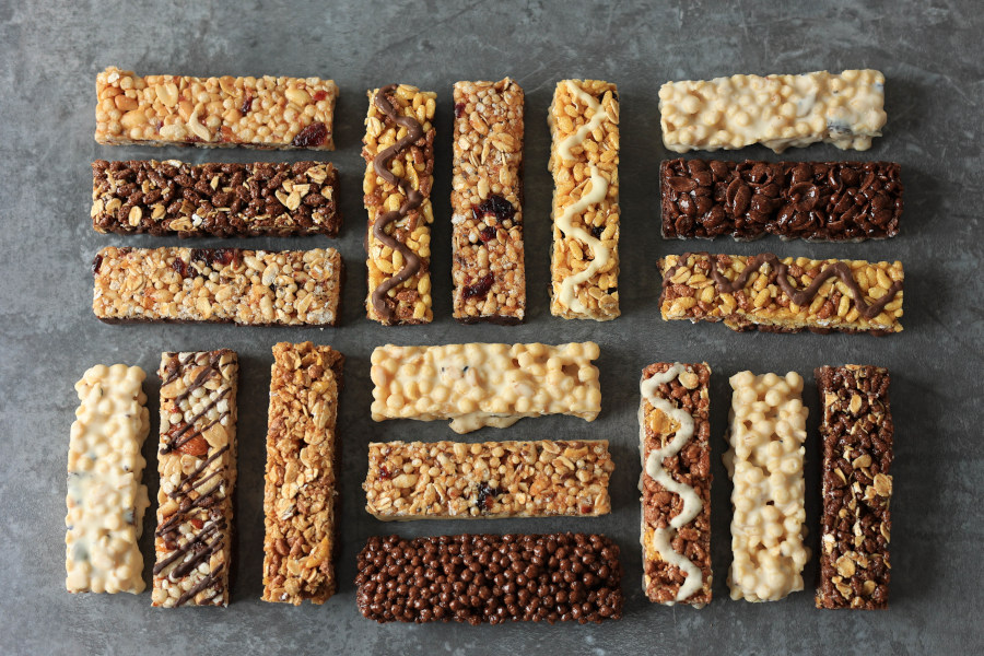 Verschiedene Müsliriegel und Snackriegel auf grauem Hintergrund.