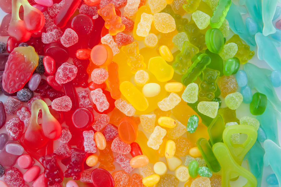 Bunte Mischung aus Fruchtgummis und Süßigkeiten als Regenbogen-Hintergrund.