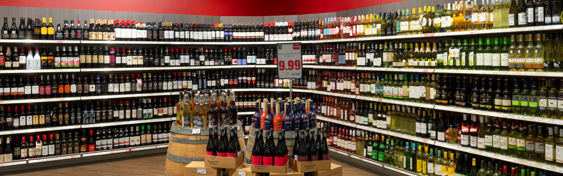 Große Wein- und Spirituosenabteilung mit vielen Flaschen im Supermarktregal.