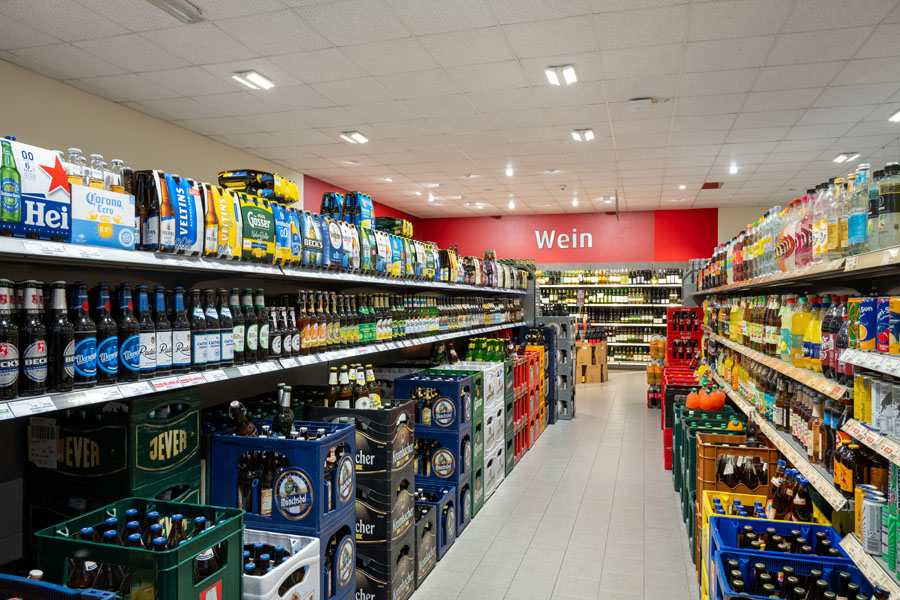 Getränke-Gang im Supermarkt mit Bierkästen, Softdrinks und Weinregalen.